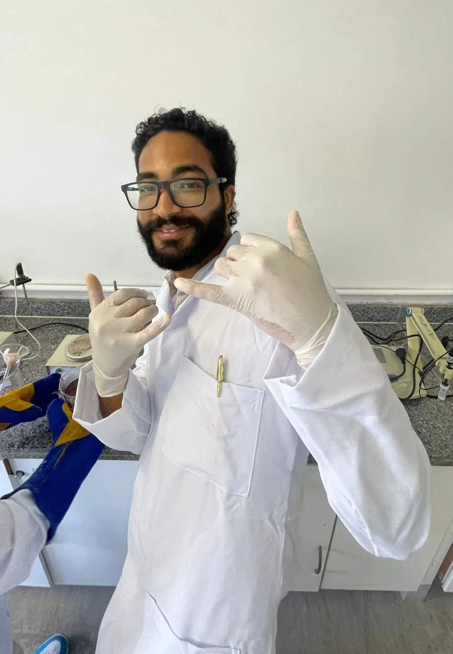 Daniel P Francisco smiling in a lab coat and gloves at the laboratory bench