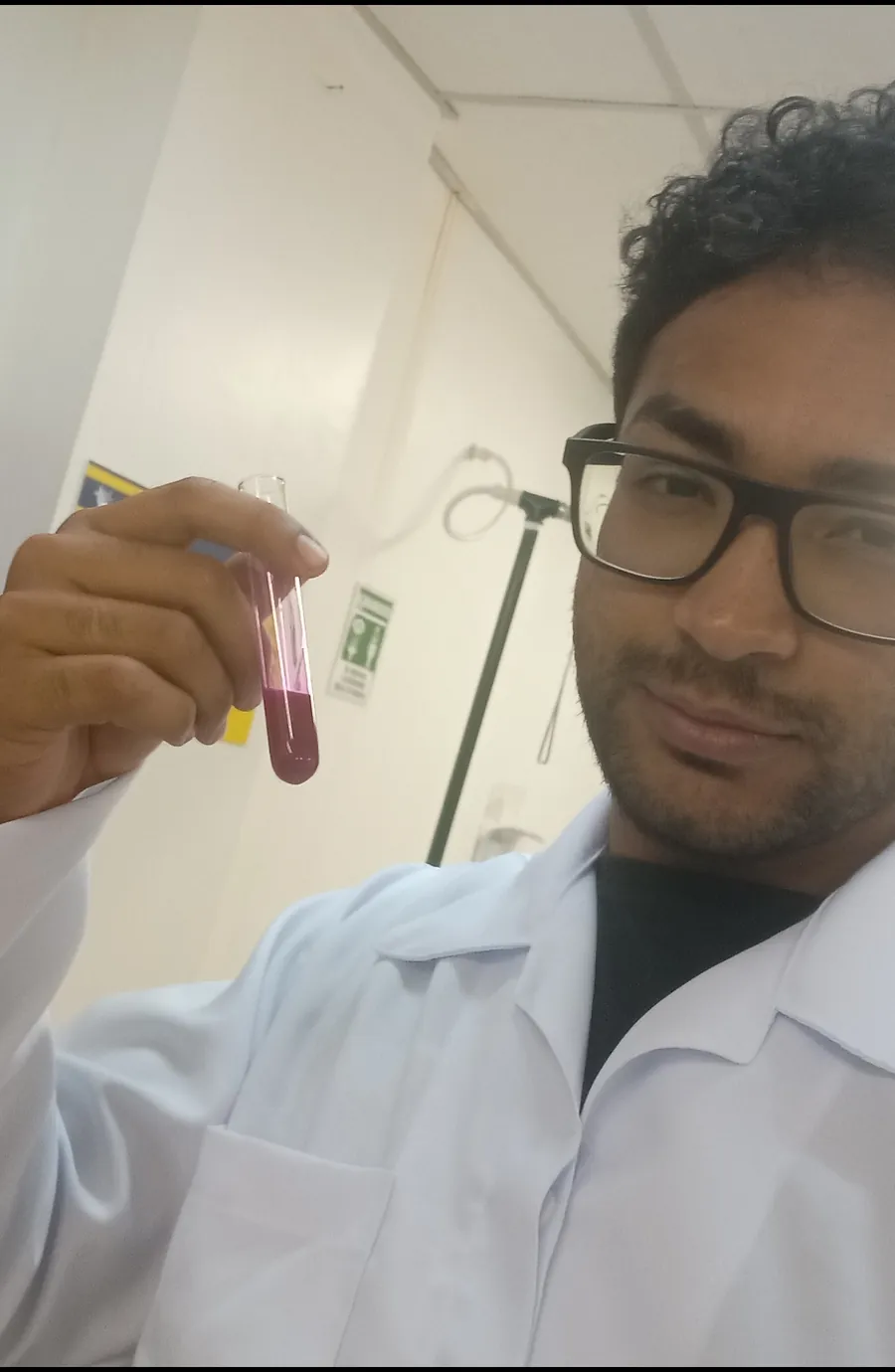 Daniel P Francisco in a lab coat holding a test tube with a purple solution